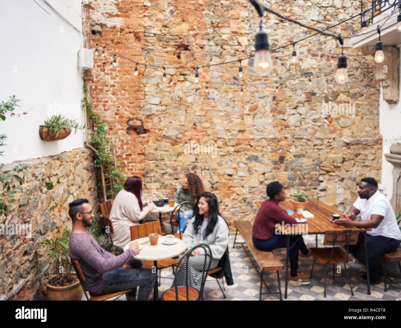 Diverse Leute sprechen miteinander über Kaffee in einem Cafe im Innenhof Stockfoto