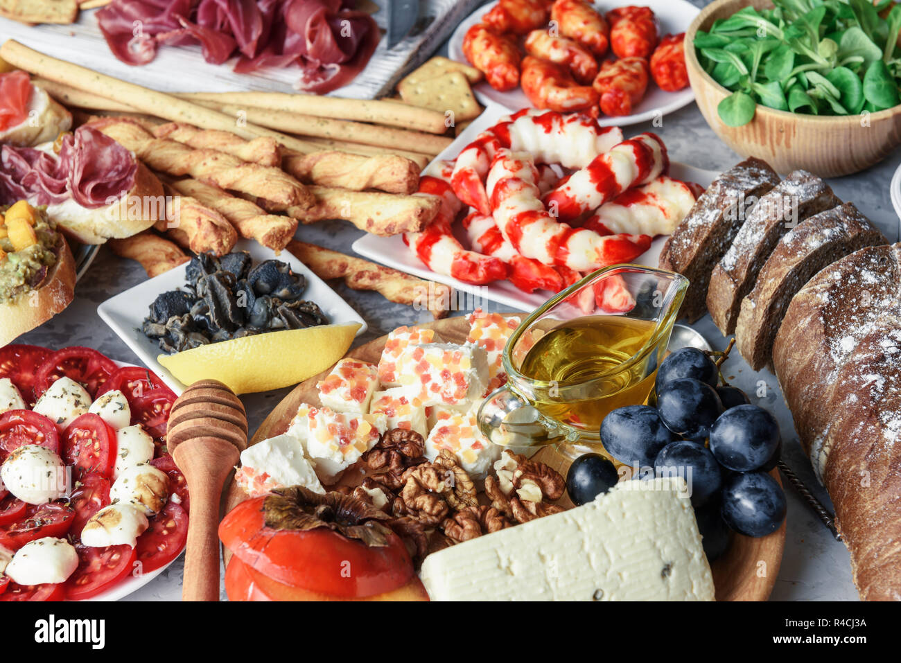 Italienische Antipasti Snacks. Brushettas, Käse Vielfalt, Garnelen, Lachs, Oliven, Schinken mit Birne, Salami und Schinken über Graues grunge Tabelle Stockfoto