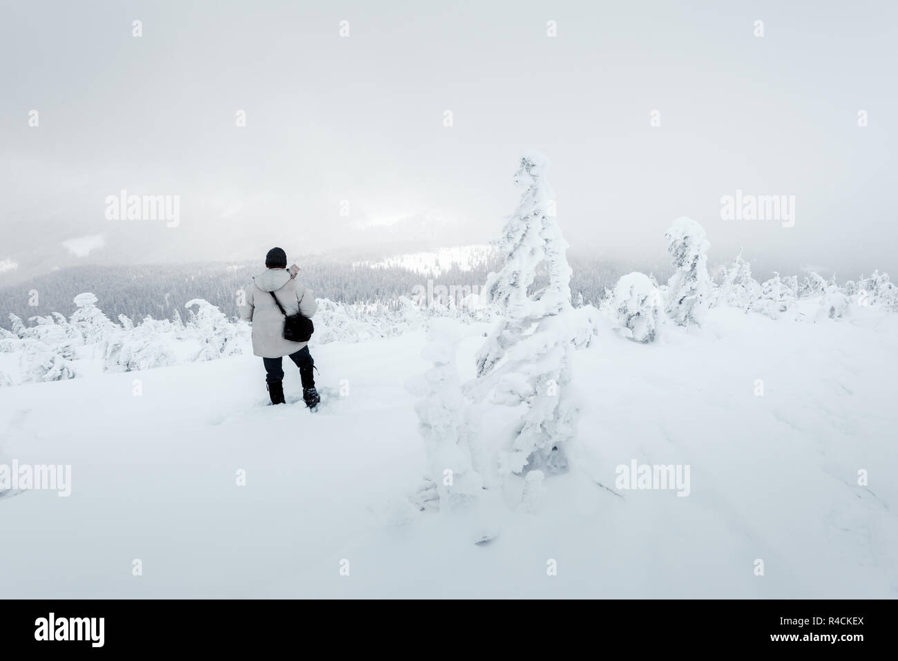 Allein Fotograf am Berg im Schneesturm mit einem Rucksack im Winter. Travel Concept. Karpaten. Landschaftsfotografie Stockfoto