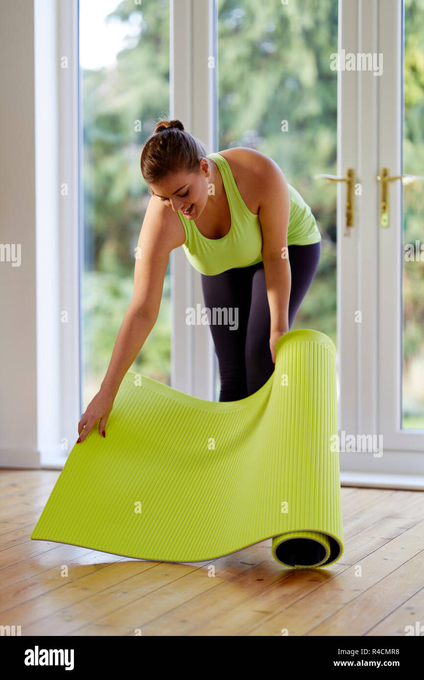 Frau, die eine Yogamatte ausrollt Stockfoto