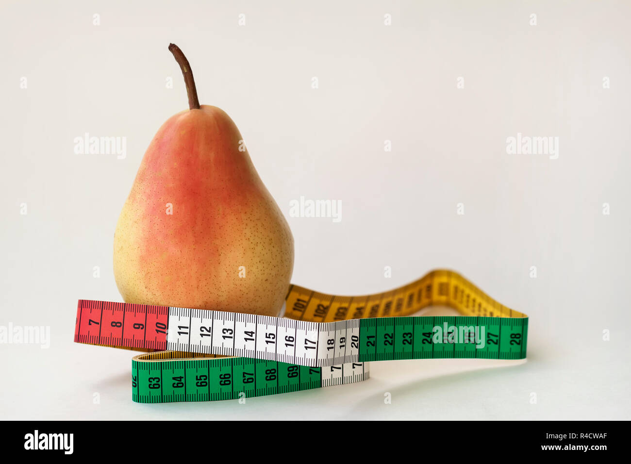 Eine reife Birne und Maßband auf hellem Hintergrund, Konzept für einen gesunden Lebensstil, Ernährung, Kontrolle von Übergewicht Stockfoto