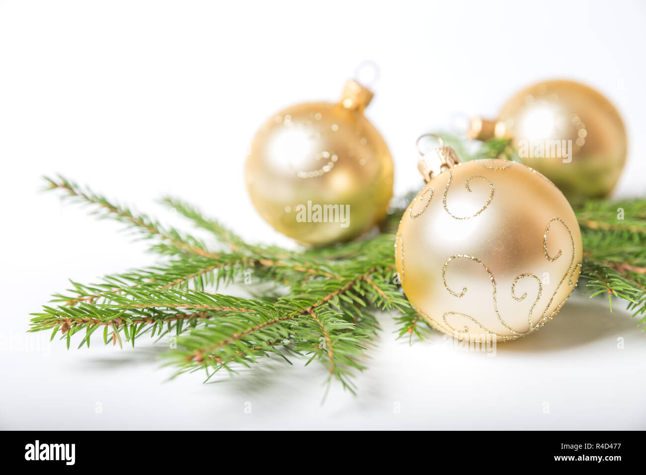 Weihnachtsschmuck, drei goldene Kugeln aus Glas liegen auf Zweig der Weihnachtsbaum, auf weißem Hintergrund Stockfoto
