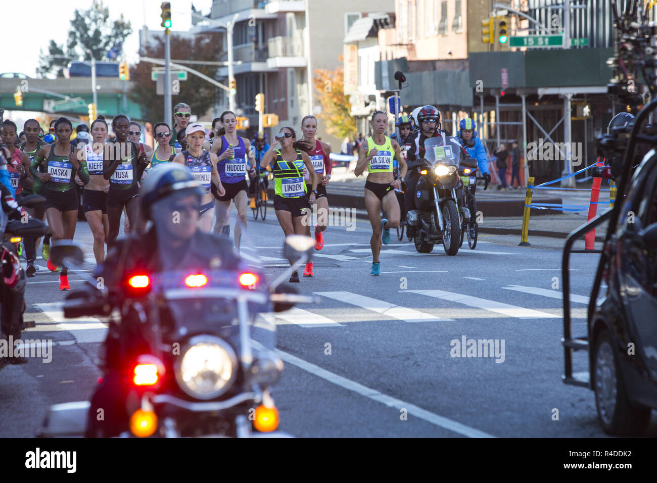 Läufer Kreuzfahrt auf der 4th Avenue in Brooklyn, während der ersten 3. des 2018 in New York City Marathon. Vorderen Läuferinnen flankiert von Polizei und Presse. k Stockfoto