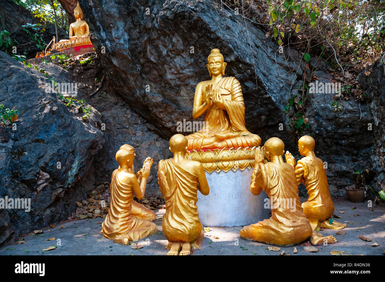 Goldenen Buddhas mit Jüngern mit Händen in der Lehre gehalten ( vitarka, Lehre mundra) im felsigen Einstellung auf Mount Phousi, Luang Prabang, Laos Stockfoto