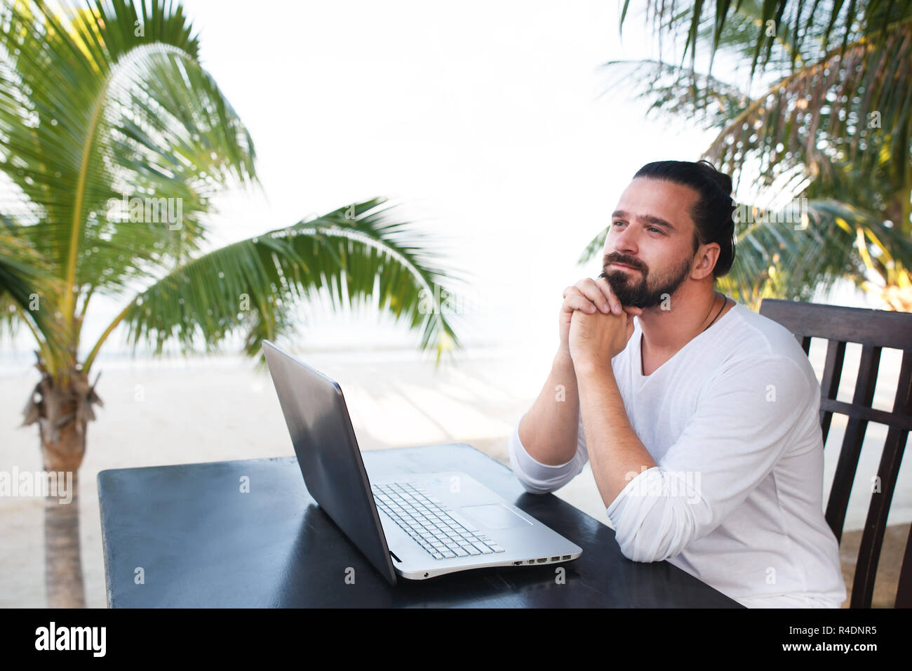Man entspannt am Strand mit Laptop, Freelancer Arbeitsplatz, Traumjob Stockfoto