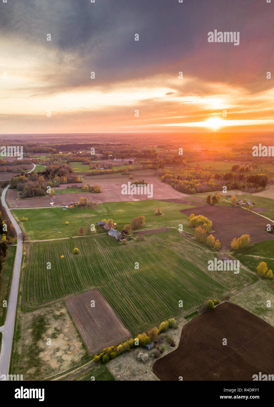 Antenne Drone Foto von einem Dorf mit Wiesen in schöner Frühling Farben in Abend Umgeben mit Sonnenuntergang über es Stockfoto