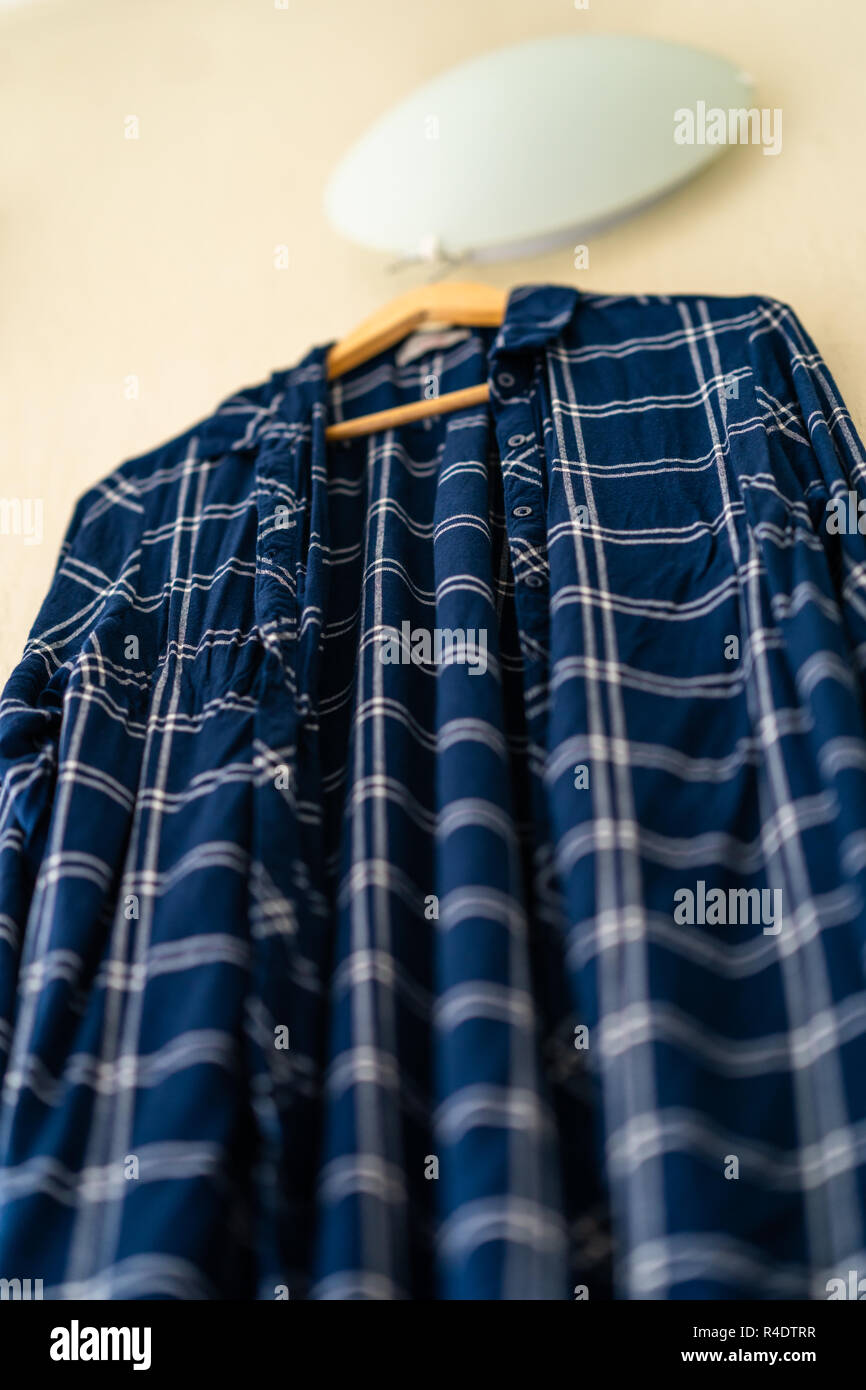 Blaues T-Shirt mit Streifen an der Wand im Wohnzimmer - isoliertes Objekt, teilweise unscharf Stockfoto