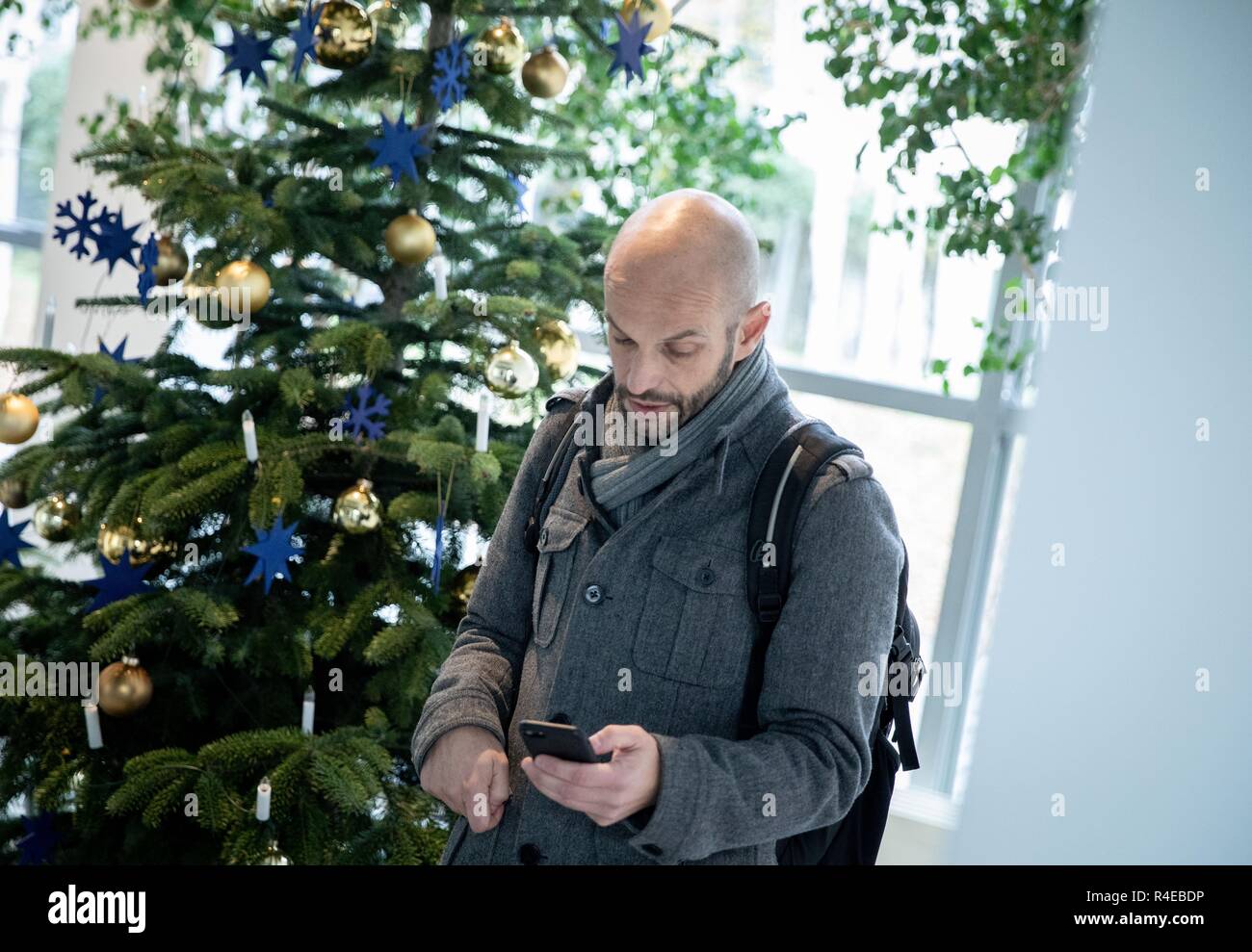 Berlin, Deutschland. 27 Nov, 2018. Der SPD-Abgeordnete Marco Bülow blickt auf sein Handy neben einem Weihnachtsbaum vor einer Pressekonferenz. Der 47-jährige seinen Rücktritt angekündigt und von der Partei, sondern will ein nicht zu bleiben-Mitglied des Deutschen Bundestages. Credit: Kay Nietfeld/dpa/Alamy leben Nachrichten Stockfoto