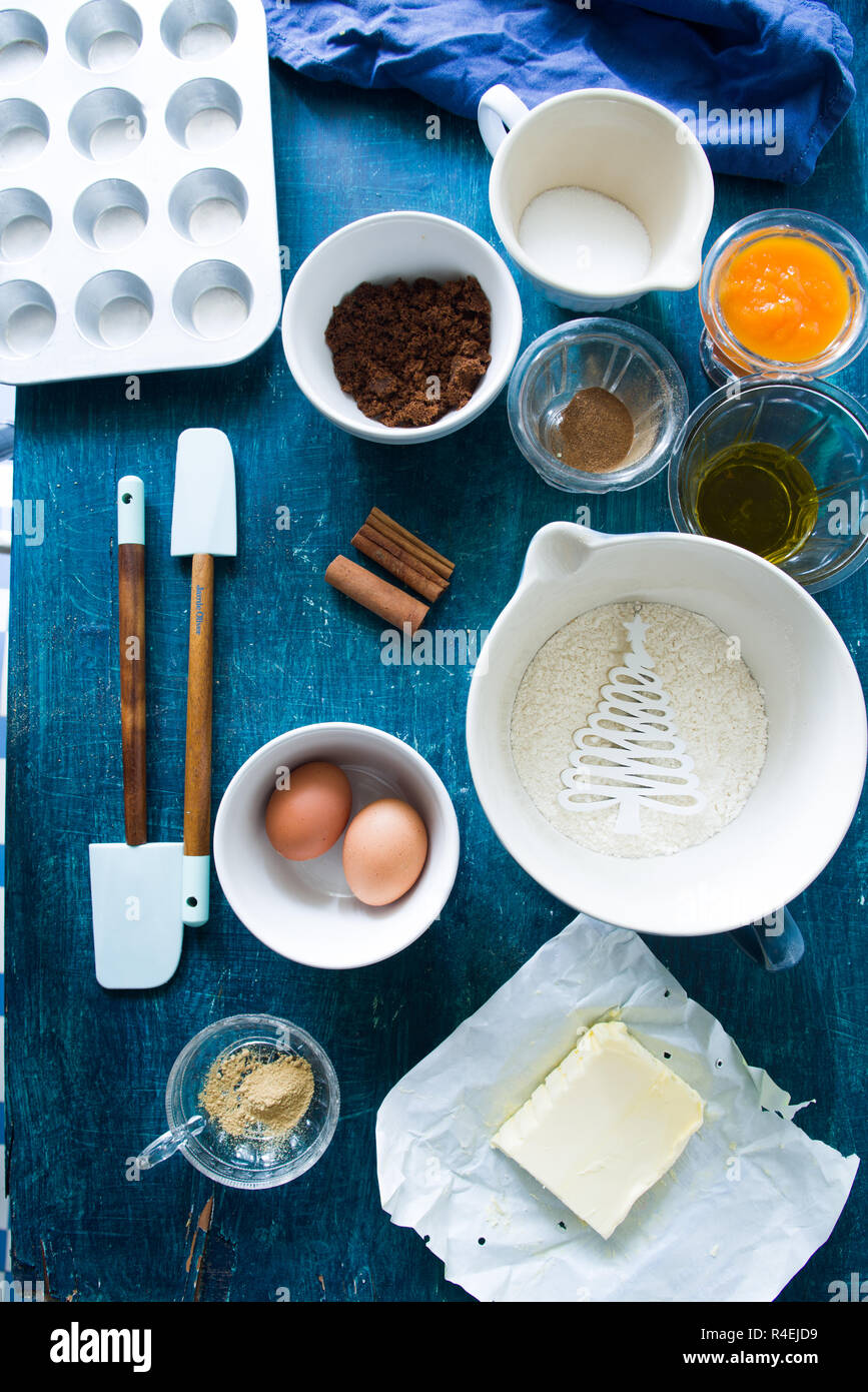 Zutaten einige muffin Kürbis für Halloween vorbereitet sind auf einer Blu rustikalen Board angezeigt, flach Draufsicht, natürliche Beleuchtung. Stockfoto