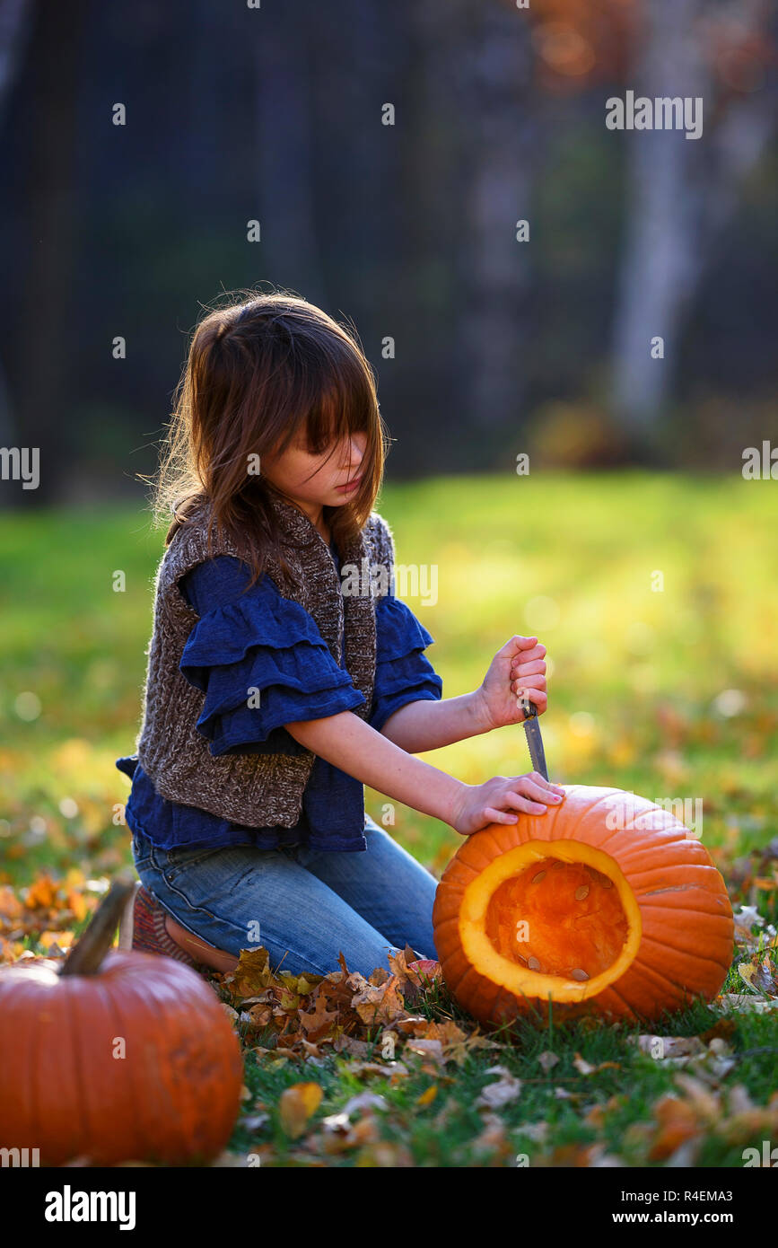 Mädchen das Schnitzen eines Halloween Kürbis im Garten, United States Stockfoto