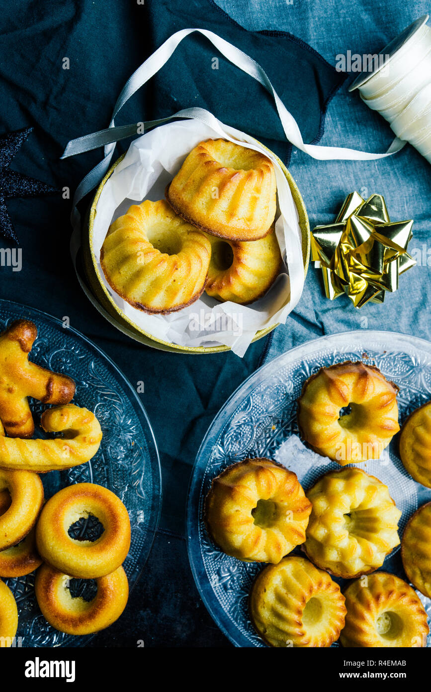 Weihnachten mini bundt Cake und Dekoration auf einem Brett mit Weihnachten Dekoration, eine goldene Paket und Schere, Ansicht von oben, flach copyspace legen. Stockfoto