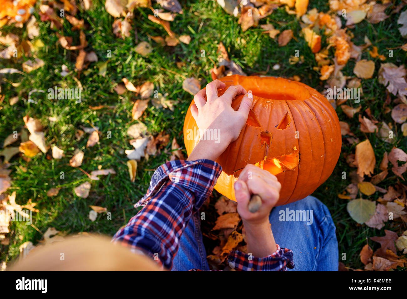 Ansicht eines Jungen Schnitzen eines Halloween Kürbis im Garten, United States Stockfoto