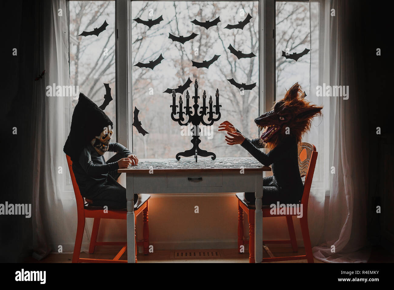 Zwei Kinder in Halloween Kostüme sitzen durch ein Fenster, ein Puzzle, United States Stockfoto