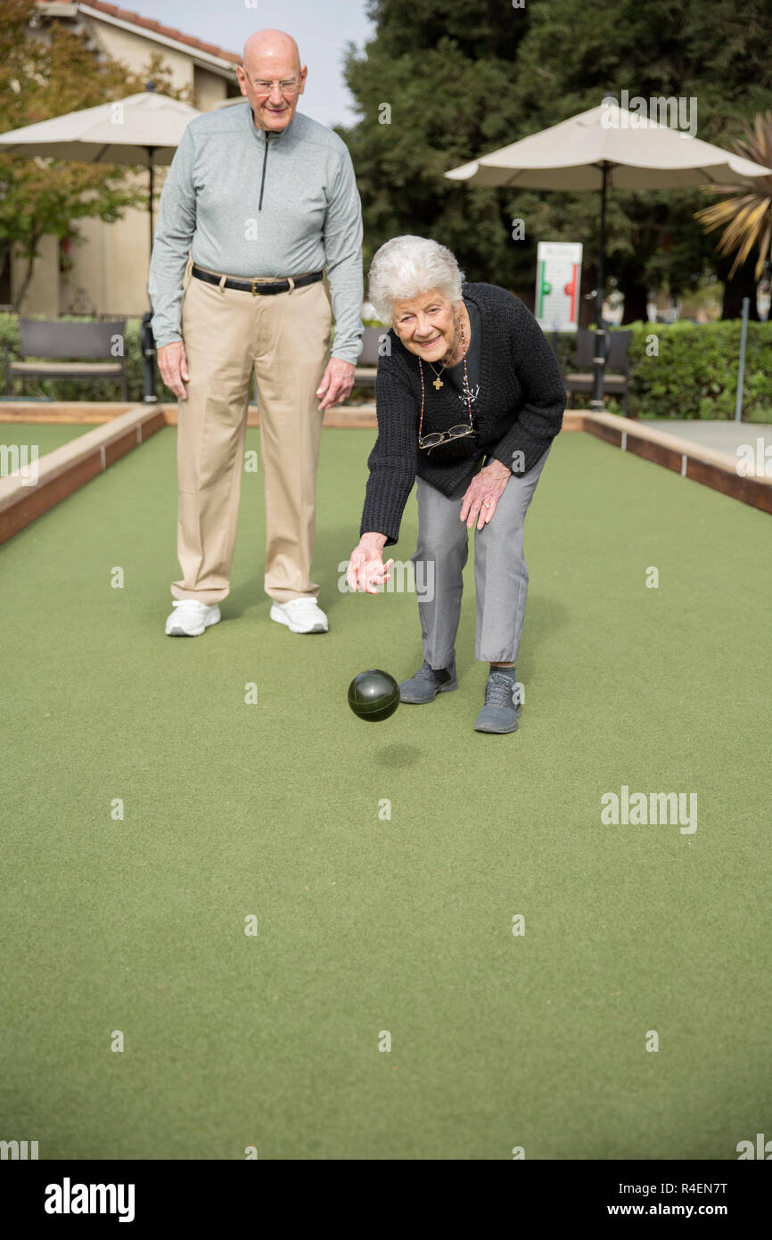 Ältere Frau, Bowling, Mann im Hintergrund Stockfoto