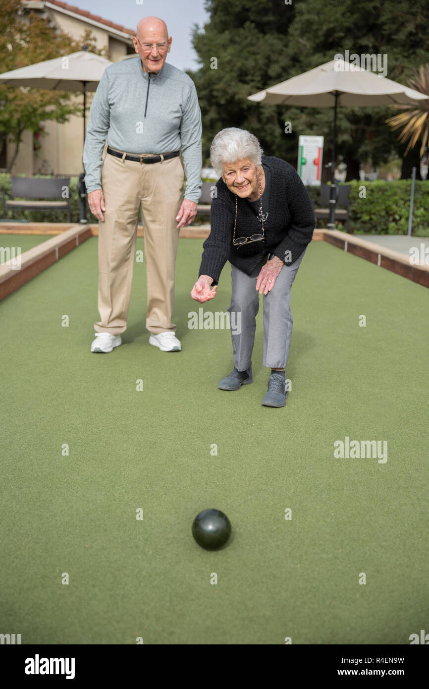 Ältere Frau, Bowling, Mann im Hintergrund. Stockfoto