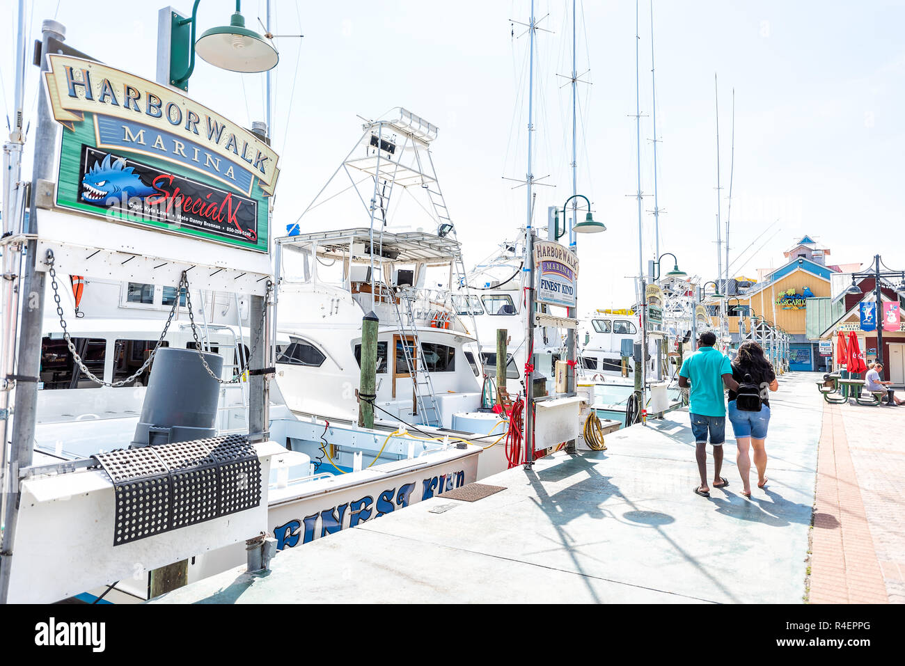 Destin, USA - 24. April 2018: Stadt Stadt Harborwalk village anmelden, indem Hafen charter boot Promenade Marina mit Paar während der sonnigen Tag in Florid Stockfoto