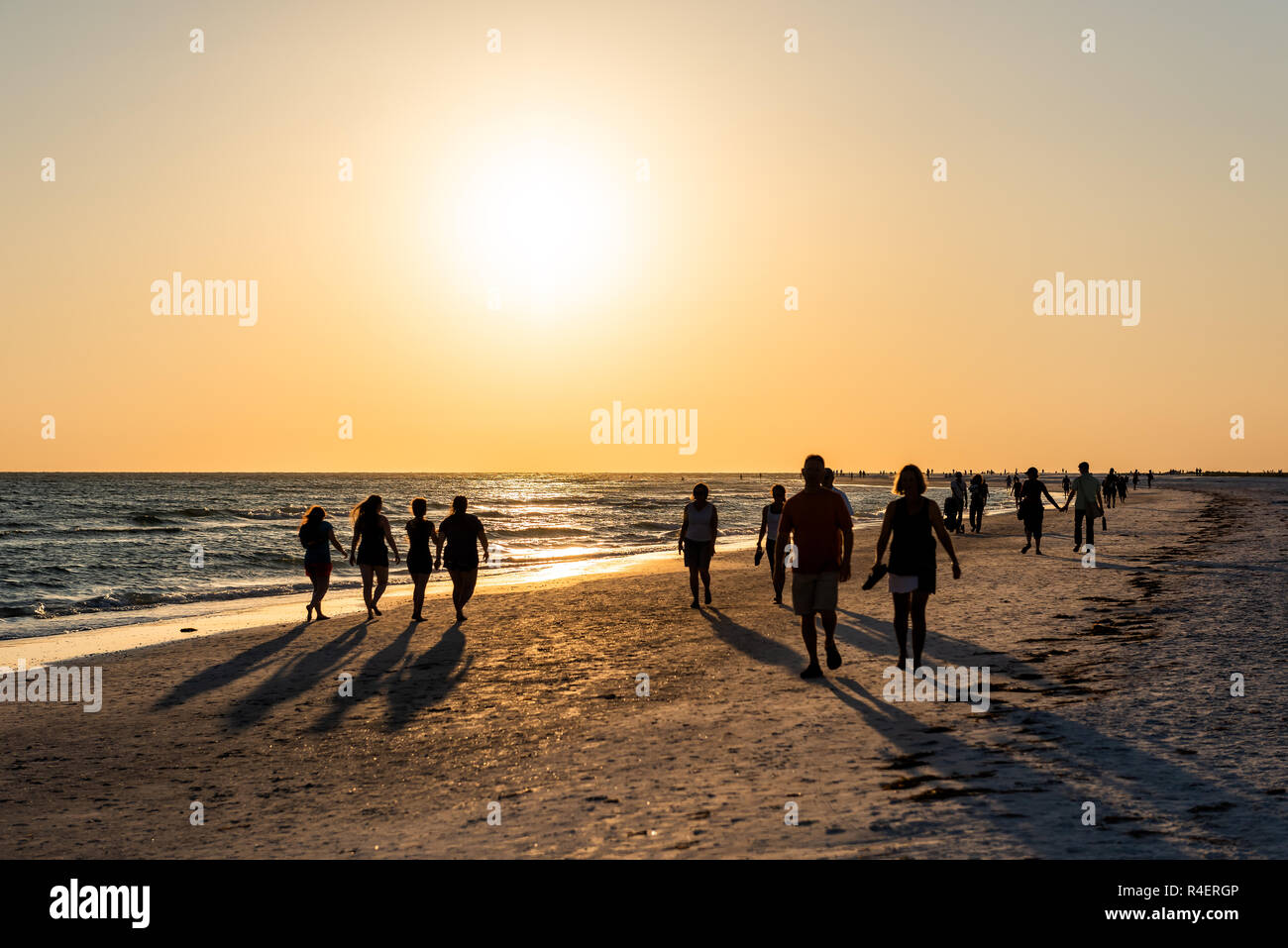 Sarasota, USA Sonnenuntergang in Siesta Key, Florida mit Küste Küste Ozean Golf von Mexiko am Strand Ufer, viele Menschen Silhouette zu Fuß durch Wellen Stockfoto