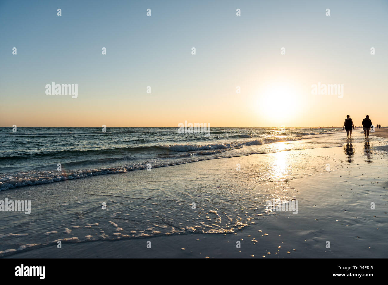 Sarasota, USA Sonnenuntergang in Siesta Key, Florida mit Küste Küste Ozean Golf von Mexiko am Strand Land, Silhouette zu Fuß durch Wellen Stockfoto
