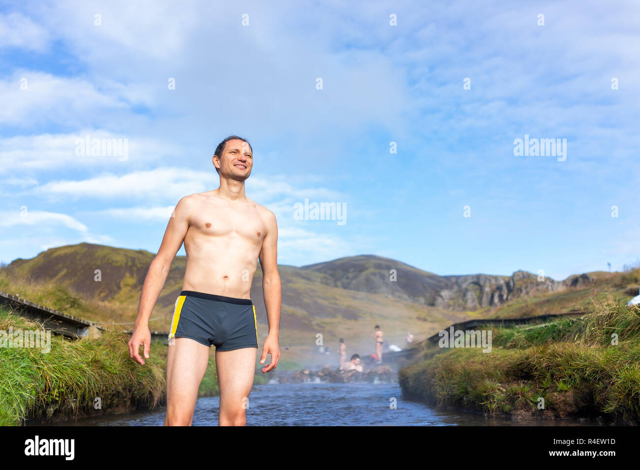 Junge glücklich Mann schwimmen Baden in heißen Quellen in Hveragerdi Reykjadalur im Süden Islands, golden circle, Felsen und Fluss Dampf, lächelnd Stockfoto