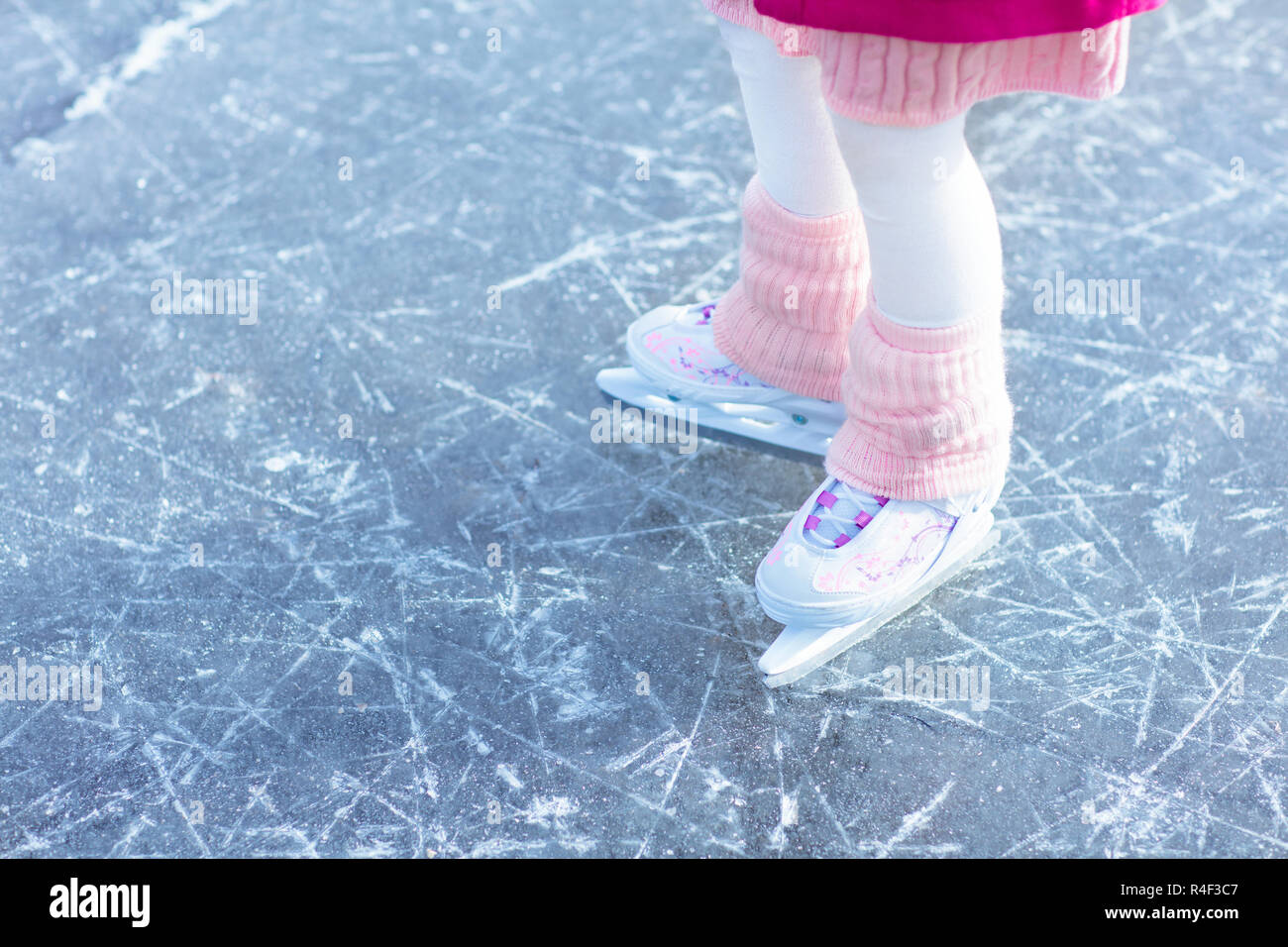 Kind Schlittschuhlaufen auf Natureis auf sonnigen Wintertag. Kinder mit Schlittschuhen. Kleines Mädchen Schlittschuhlaufen auf zugefrorenen See in Snowy Park. Schnee und Winter Spaß. Gesunde heraus Stockfoto