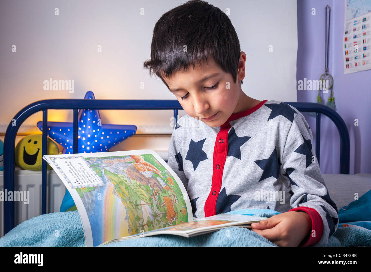 UK, Junge,7 Jahre alt liest im Bett Stockfoto