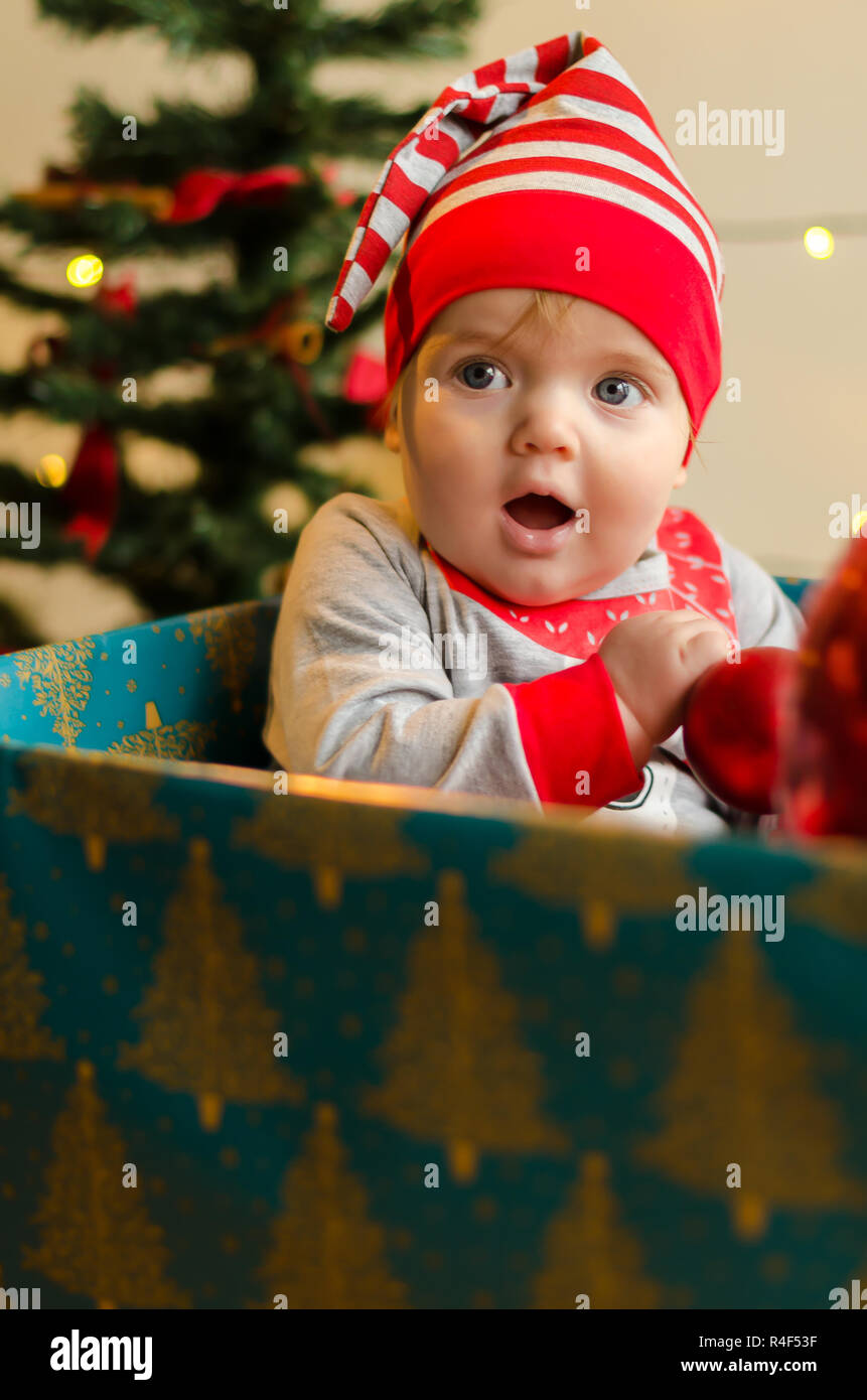 Frohe Weihnachten Baby Mädchen in ein Kästchen um Weihnachtsbaum und Dekorationen Stockfoto