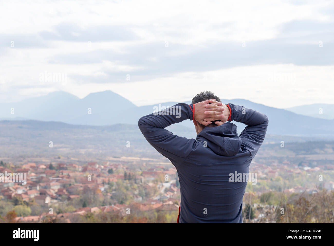 Mann streetching auf der Spitze des Hügels Stockfoto