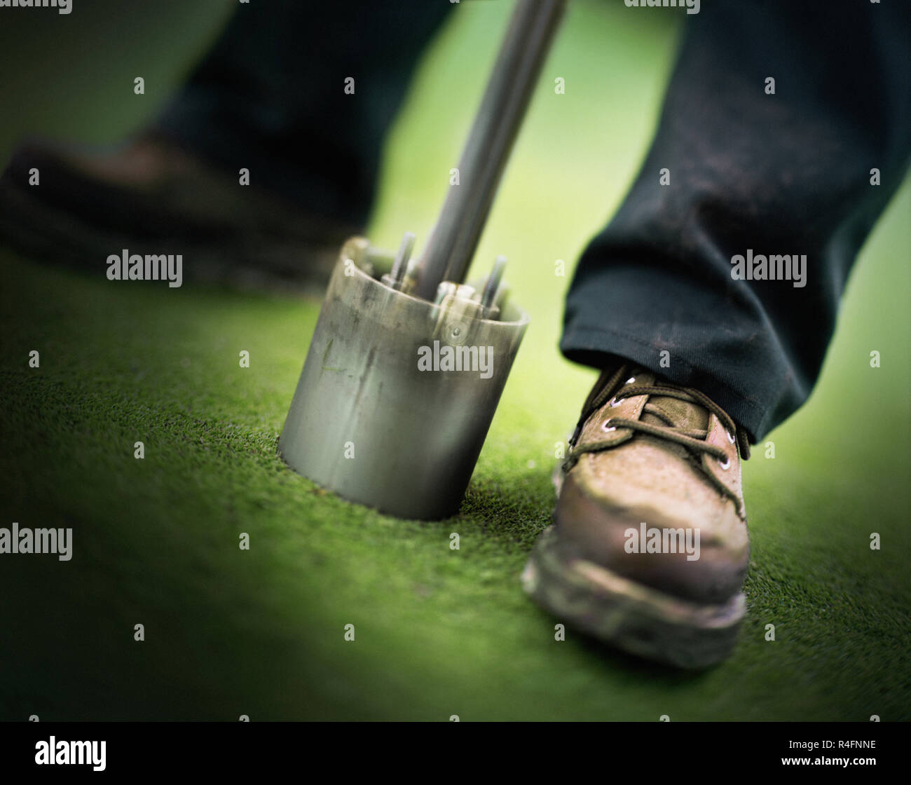 Odyssey Golf-Ad 1 Bild 1 ein Paar Füßen neben einem Pfahl. Stockfoto