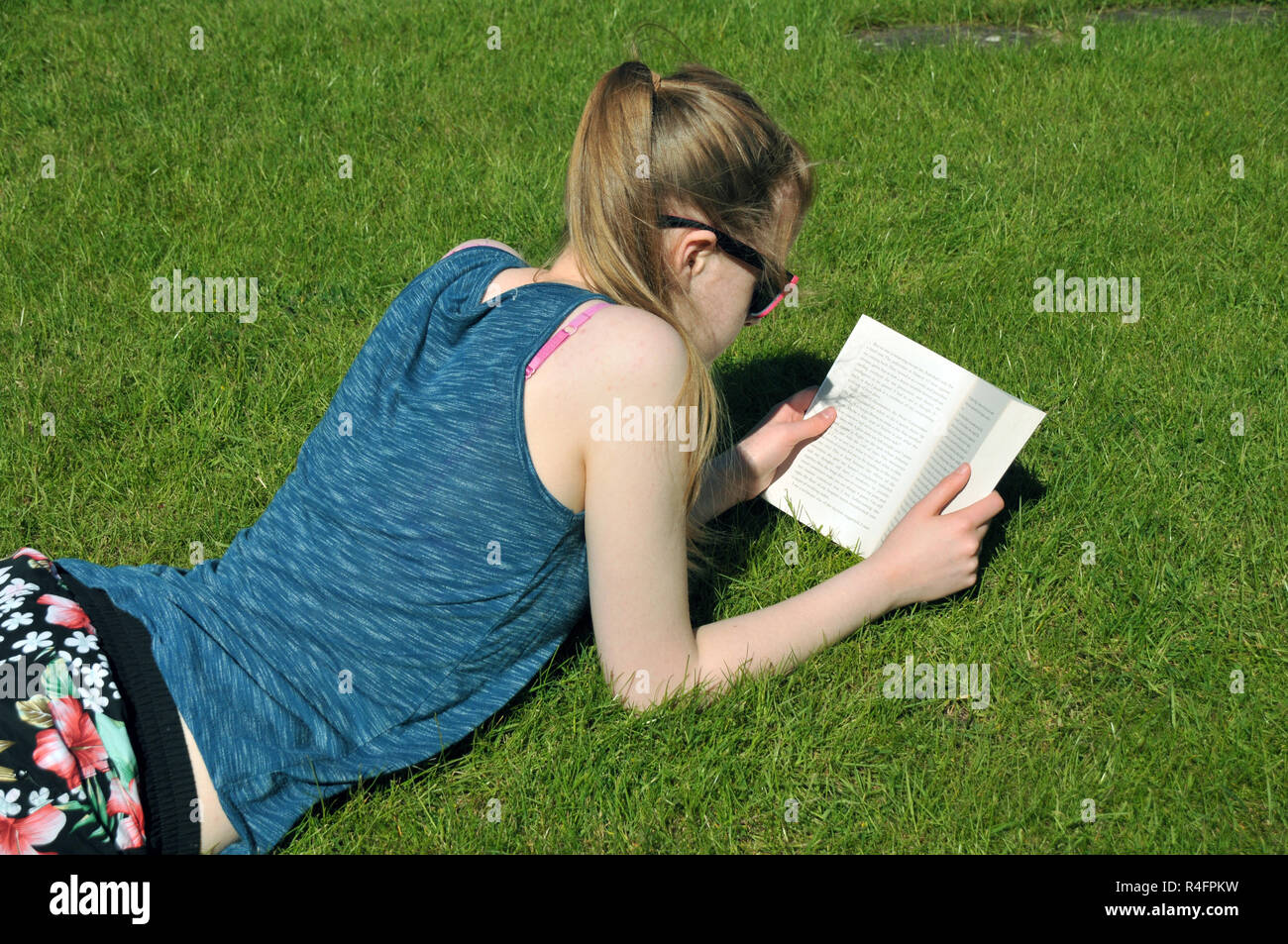 Junges Mädchen mit einem Buch im Sommer im Garten liegen. Stockfoto
