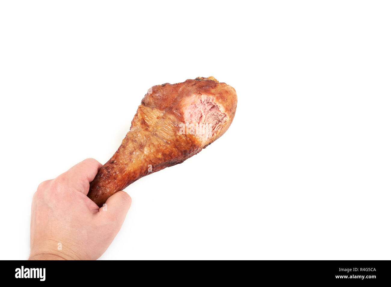 Hand mit gebratener Truthahn Bein mit Biss, auf weißem Hintergrund. Stockfoto