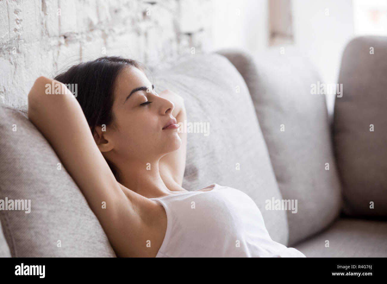 Junge Frau entspannend lehnte sich zurück auf dem bequemen Sofa Stockfoto