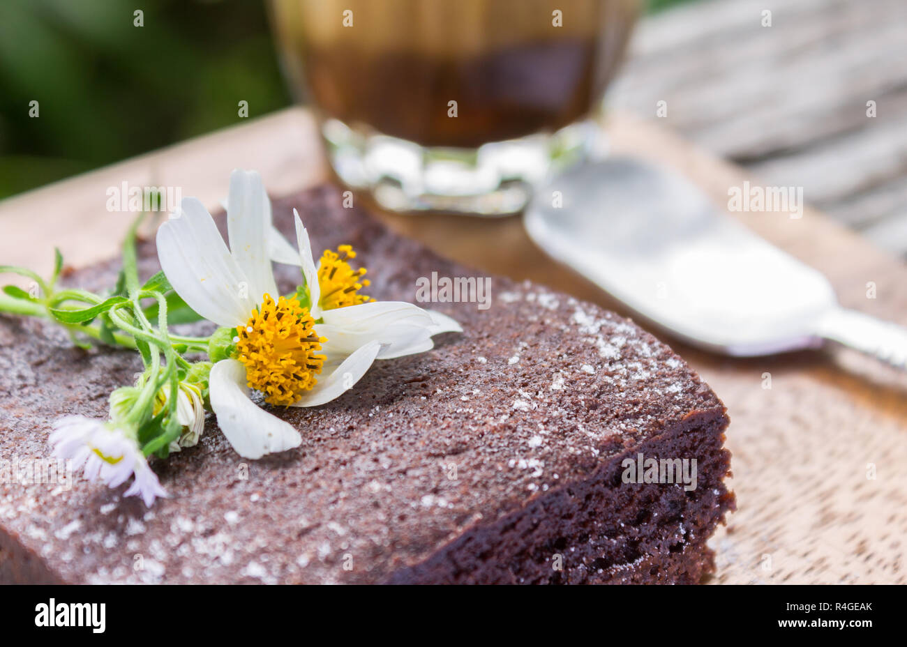 Daisy Flower auf Chocolate Brownie Kuchen mit Kaffee und Latte Löffel auf Holz Tisch links schließen. Entspannen Kaffeepause Zeit im Café des linken Rahmens Stockfoto