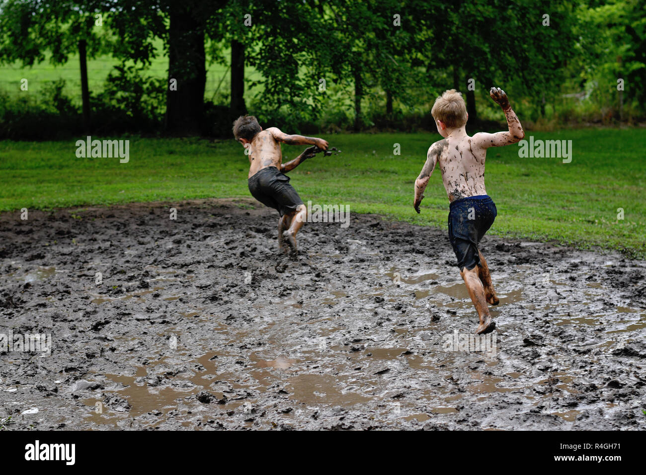 Zwei Jungen werfen Schlamm und Kämpfe in einem Schlamm kämpfen im Land Stockfoto