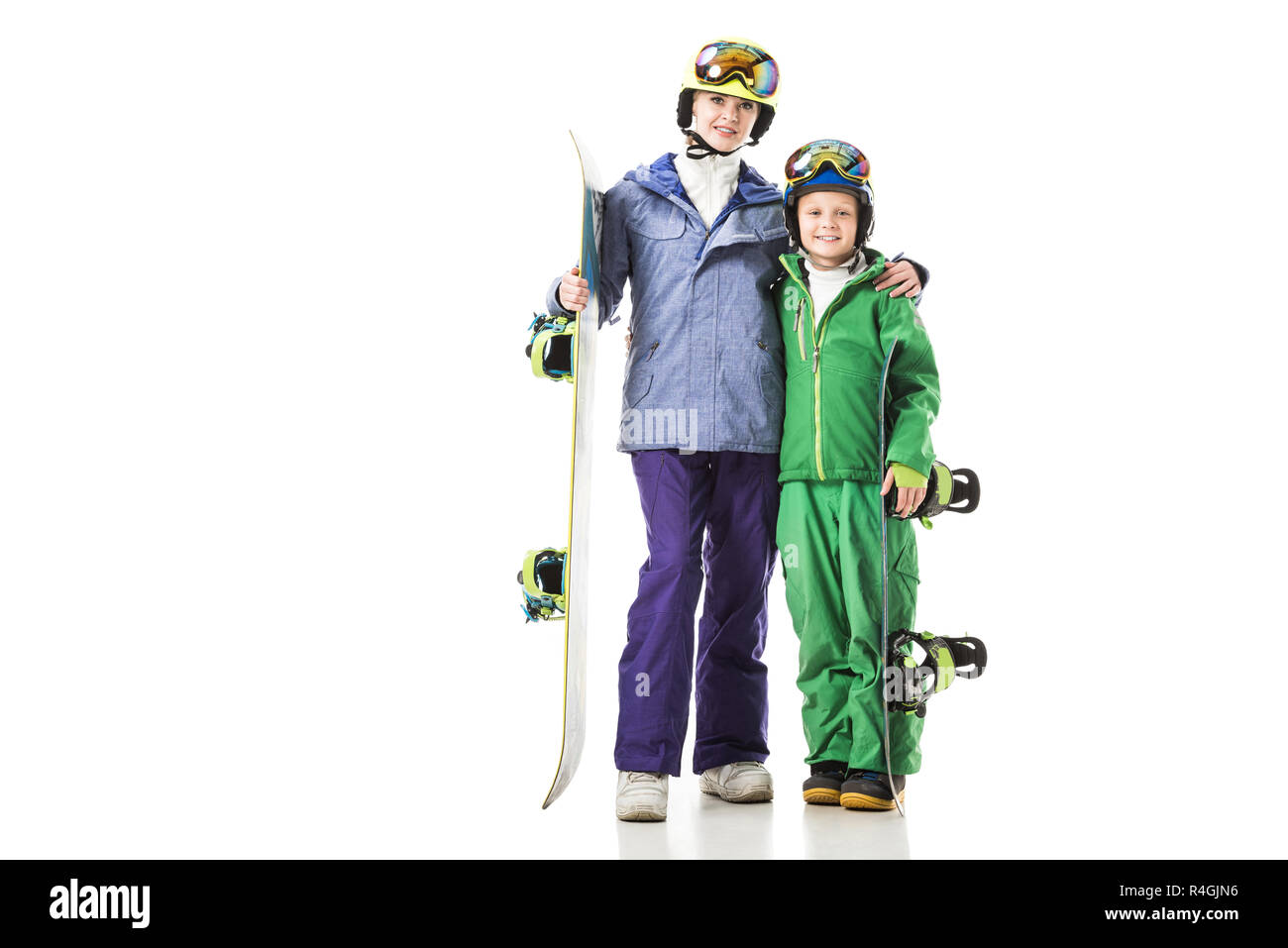 Junge Mama und jugendlichen Sohn in Ski Anzüge mit Snowboards umarmen isoliert auf weißem Stockfoto