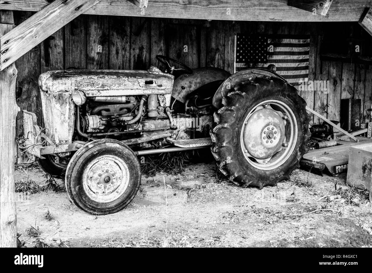 Schwarz und Weiß, ein Vintage oder antike Traktor in einem schwach beleuchteten Scheune Stockfoto