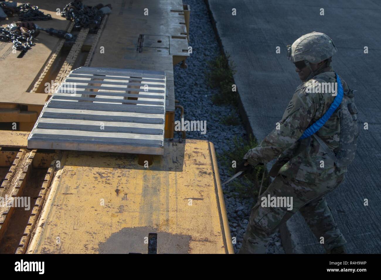 Sgt. Antonio Goard an 2nd Battalion, 69th Armored Regiment, 2. gepanzerte Brigade Combat Team, strafft eine Rampe zu einer Eisenbahn Riegel am Fort Stewart, Ga., Okt. 3, 2018 beigefügt. Soldaten gebunden Rampen zwischen den Waggons, die Fahrzeuge zu leicht von den Wagen ohne Schäden. Stockfoto