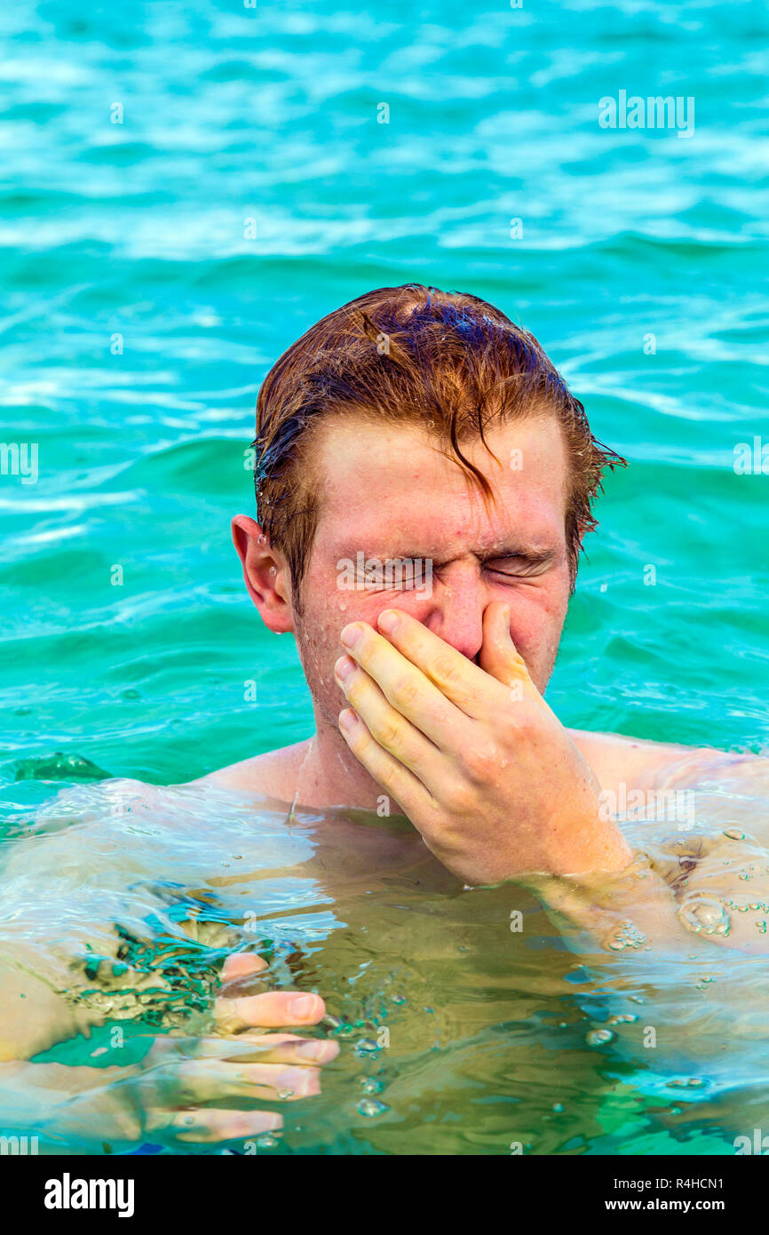 Teenager bläst seine Nase von Salzwasser Stockfoto
