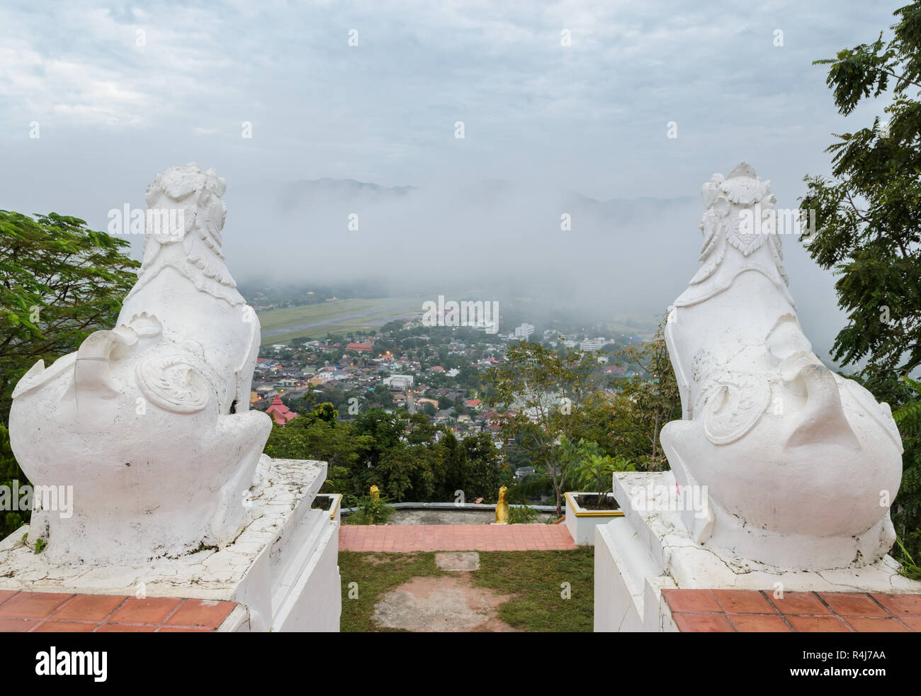 Lion Statue im Wat Phra That Doi Kong Mu mit Blick auf die Stadt von Mae Hong Son im Nebel, Thailand Stockfoto