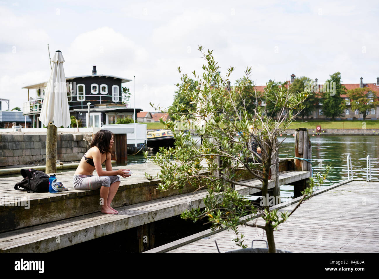 Mitte der erwachsenen Frau auf einem Pier in Kopenhagen, Dänemark, sitzen Stockfoto