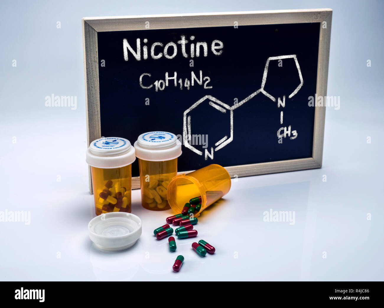 Nikotin von Hand auf einer Tafel neben Flaschen von Kapseln, konzeptionelle Image geschrieben Stockfoto