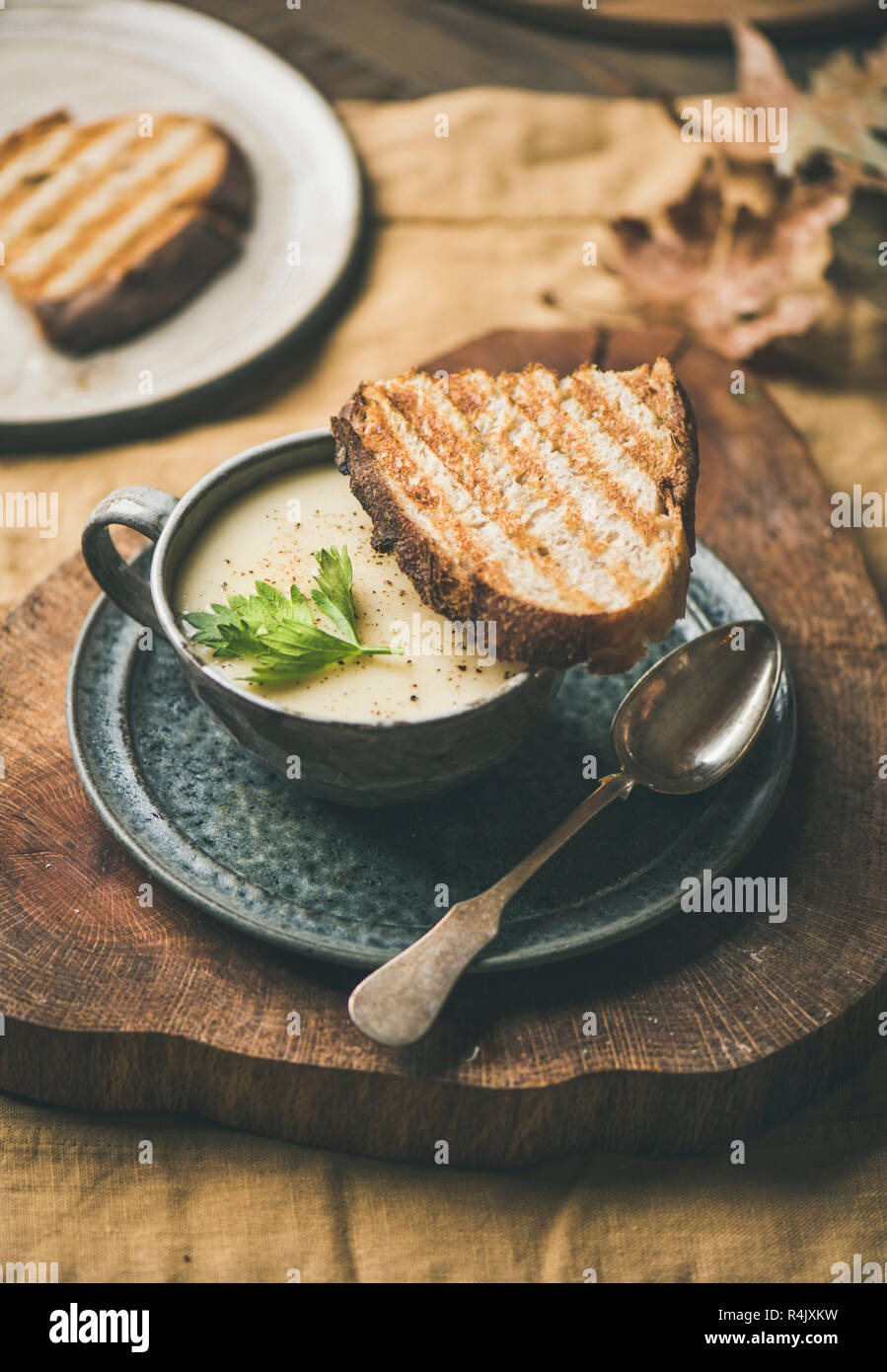 Herbst, Winter home Abendessen. Herbst Erwärmung Sellerie creme Suppe in Schale und Toast über gelb Bettwäsche Tischdecke. Komfort Essen, vegan, Vegetarisch, gesunde und Stockfoto