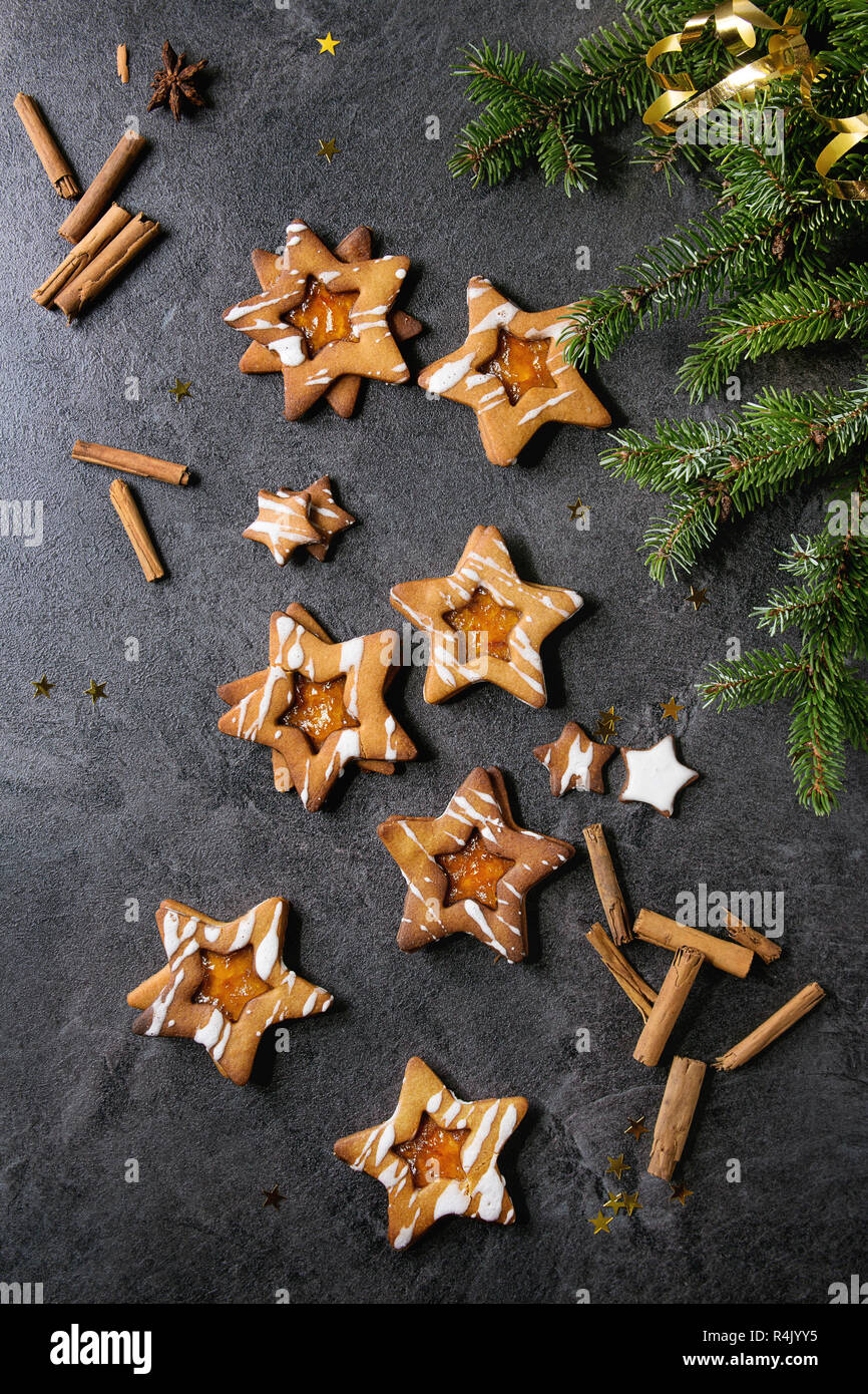 Hausgemachte Weihnachten neues Jahr Stern Zucker karamel Kekse mit Zuckerguss und orange Zitrus Marmelade, Zimtstangen und Anis über schwarzen Textur backgro Stockfoto