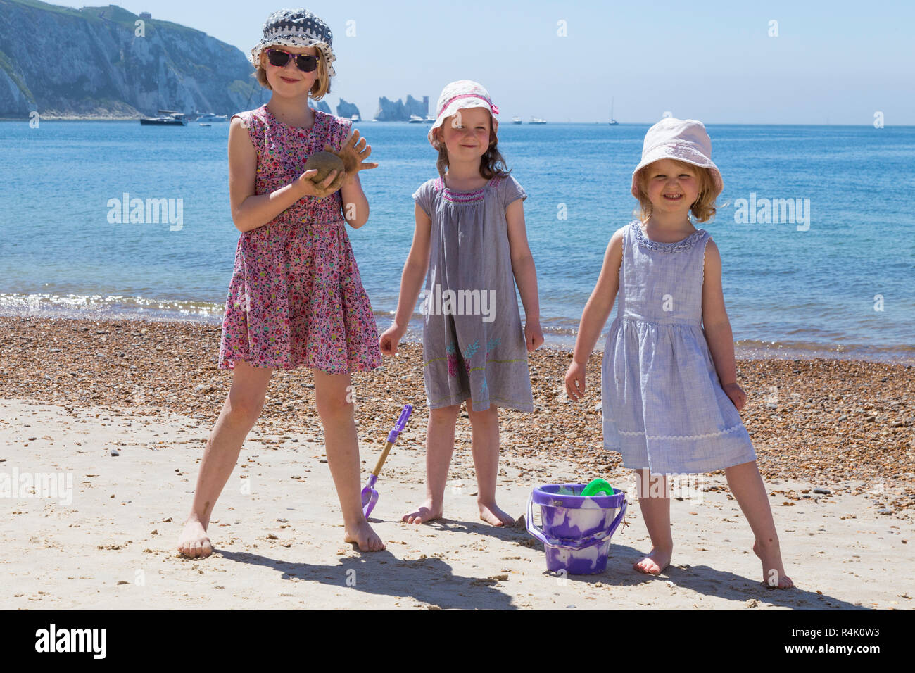 Drei Schwestern, junge Mädchen, genießen Sie eine Familie spielen am Strand von Alum Bay auf der Isle of Wight, Großbritannien. Sie tragen Hüte und Kleider/Kleidung von der Sonne (98) zu schützen Stockfoto