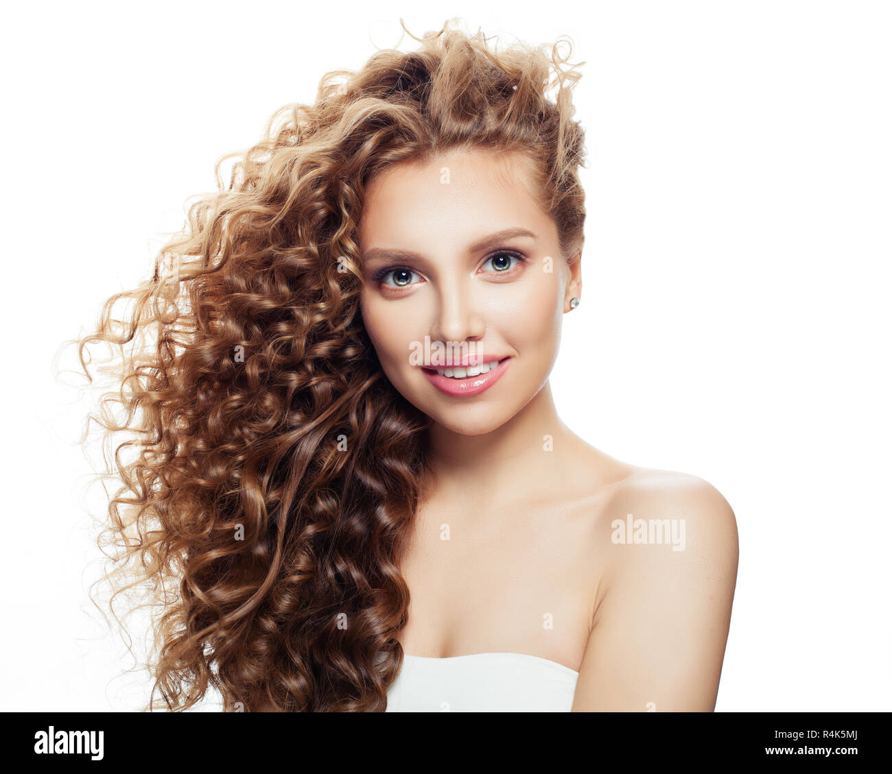Junge lächelnde Frau mit gesunder Haut und Blasen gewelltes Haar isoliert auf weißem Stockfoto