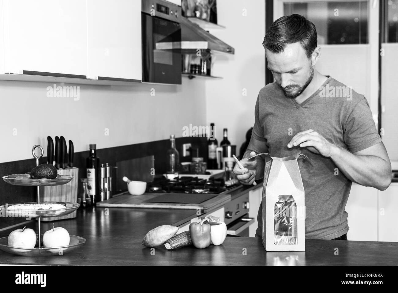 Junger Mann öffnet sich ein Paket von frischen Zutaten ein gesundes Abendessen zu machen Stockfoto