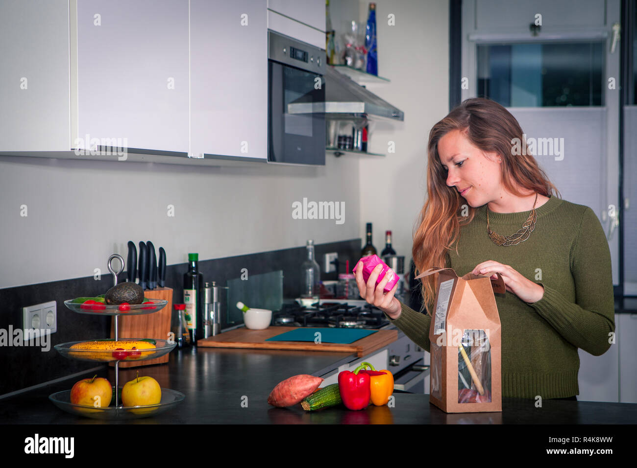 Junge Frau steht in der Küche und lesen das Paket für Anweisungen Stockfoto