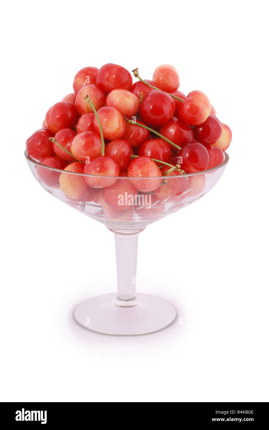 Viel reife rote Kirschen in einem Weinglas auf weißem Hintergrund Stockfoto