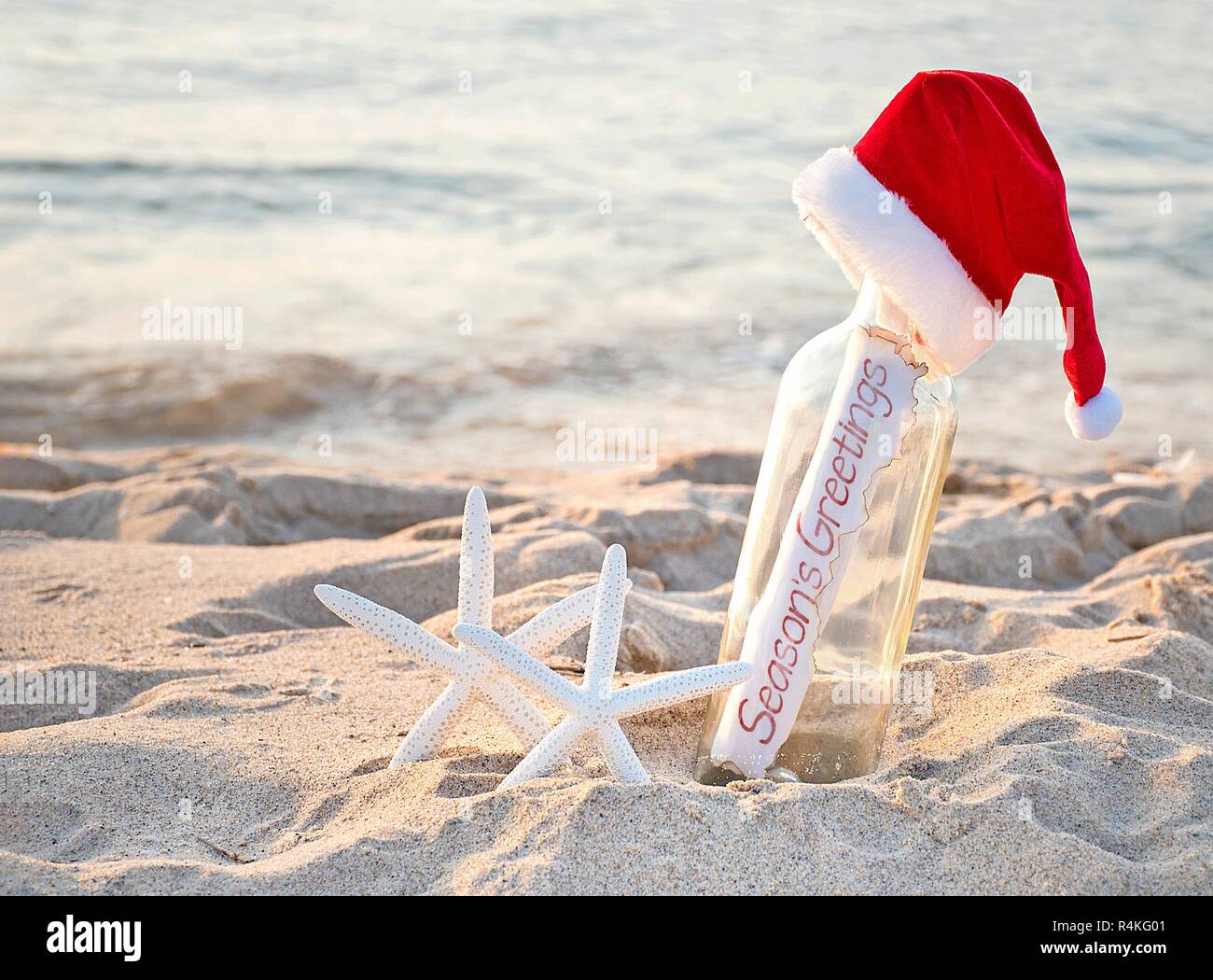Santa Hut auf Nachricht in einer Flasche mit weißer Seestern in Sand und Weihnachtsgrüße anmelden Stockfoto
