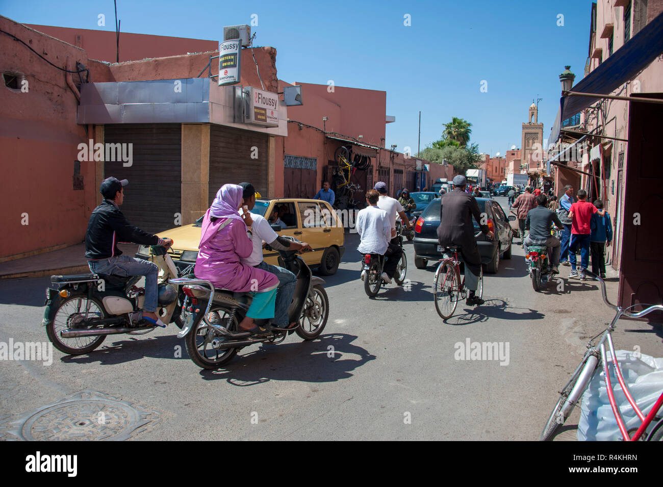 18-04-11. Marrakesch, Marokko. Eine geschäftige Straße Ecke außerhalb der Medina, mit Fußgängern, Autos, Mopeds und Motorroller alle konkurrierenden für den Weltraum. Foto © S Stockfoto