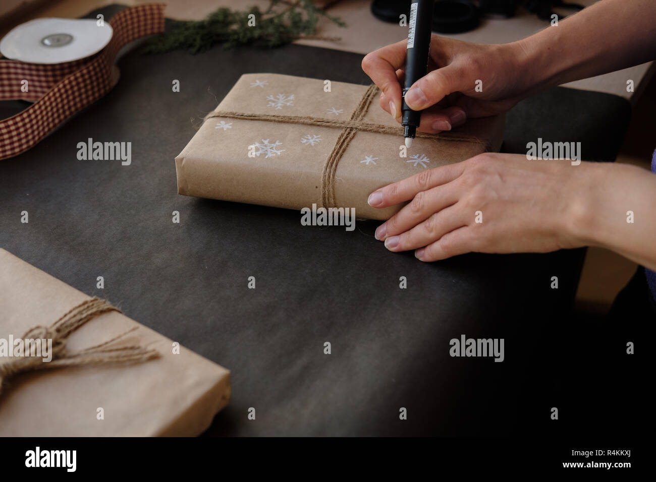 Frau Zeichnung auf Papier Schneeflocken Paket Weihnachten, Geschenk auf schwarzem Hintergrund. Weibliche Hände malen auf Geschenke für Winterurlaub. Weihnachten, Ne Stockfoto
